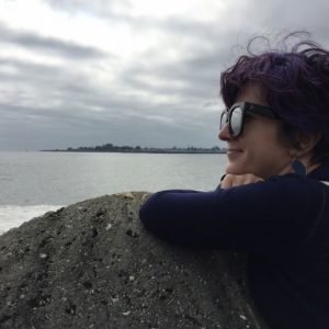 Mariel Aquino leaning against a rock with ocean and landmass in the background