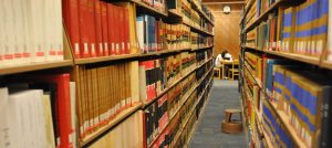 Photograph of 2 bookshelves angled towards a student studying.