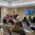 a room of people watch as a man in a yellow shirt presents