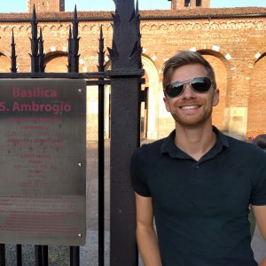 Chris Nofziger posing next to a metal gate with a brick building in background