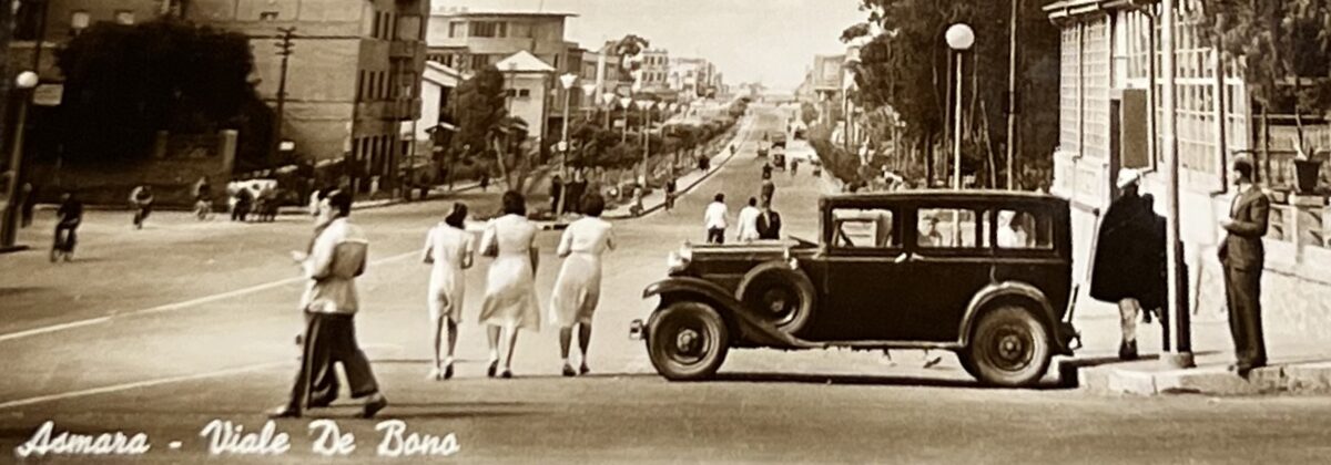 a sepia photo of a road with an old black car at the forefront