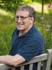 Maurice_Isserman on a bench with flowers in background