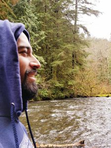 Isidro González in profile with body of water and trees behind him