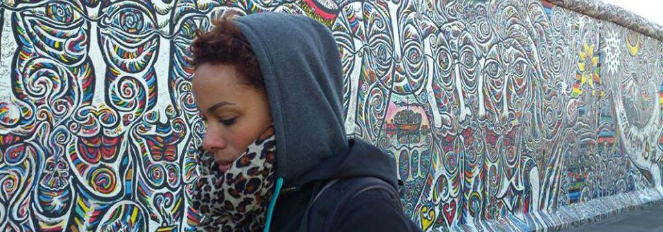 A young, ethnic women walks along a muralled wall. She is one of the faces of a new, multicultural Germany.