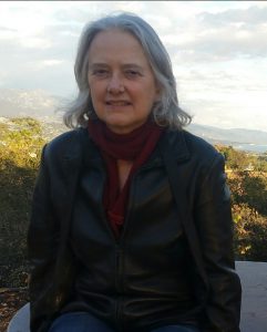 Sharon Farmer headshot from an elevation with treetops and valley and ocean in background